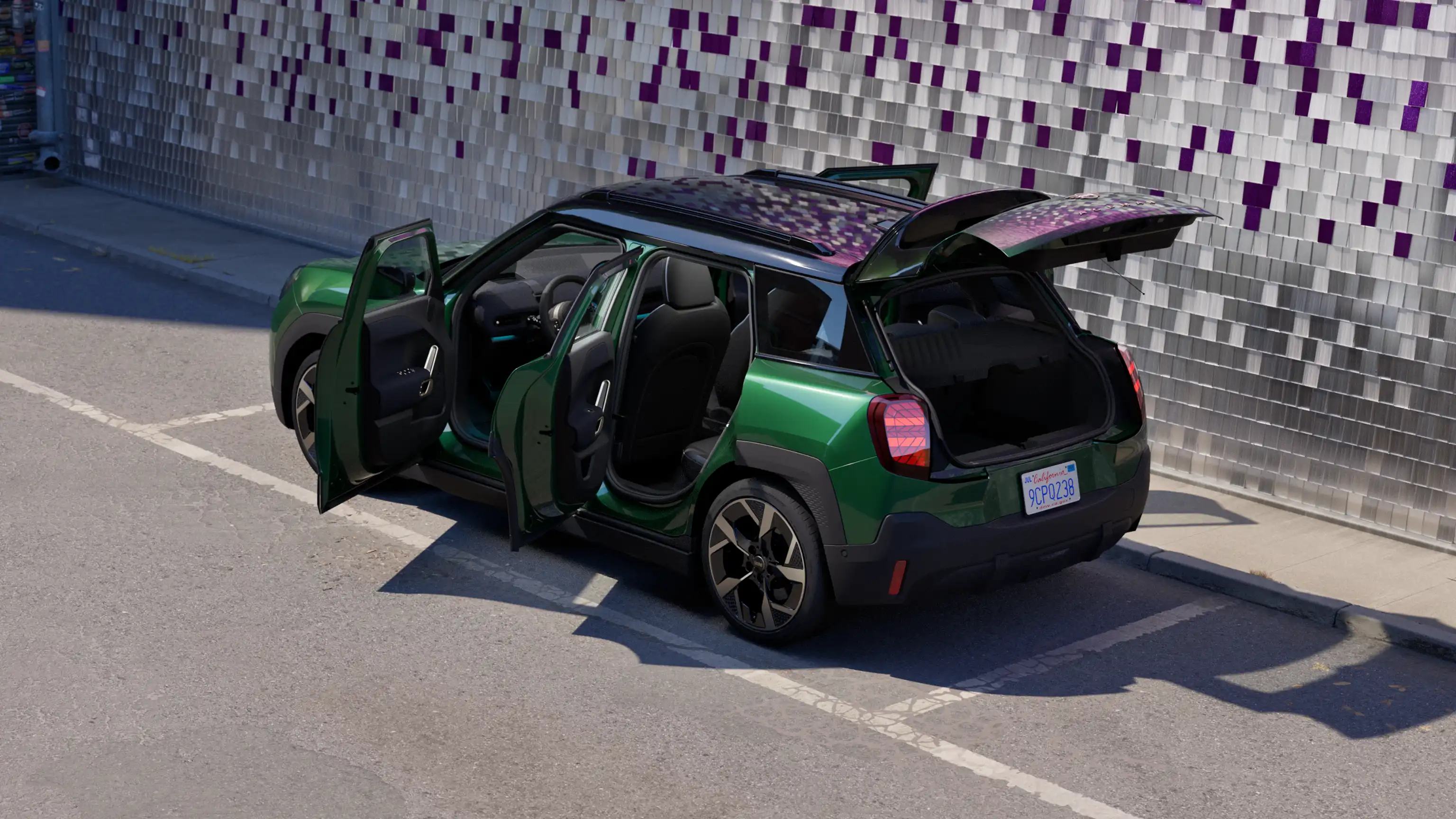 Aizmugures sānskats – stāvvietā novietots pilnībā elektriskais MINI Aceman British Racing Green krāsā, ar atvērtām durvīm un krāsainu sienu fonā