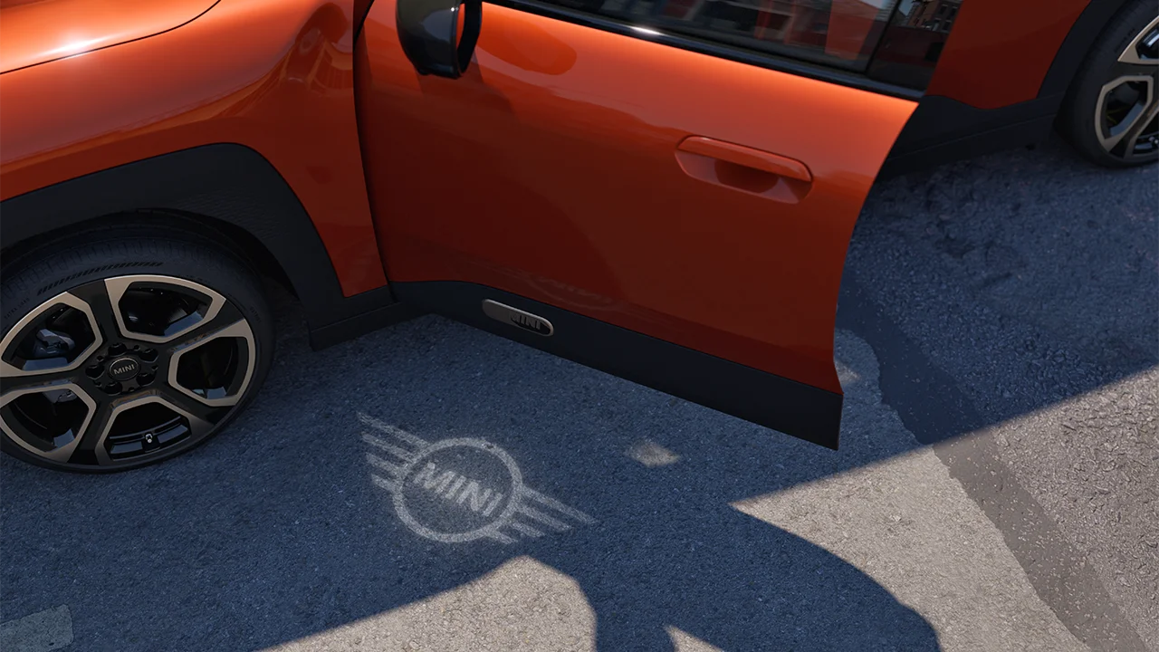 Ārējais skats – pilnībā elektriskais MINI Aceman ar atvērtām durvīm un MINI logotipa sagaidīšanas gaismu uz zemes