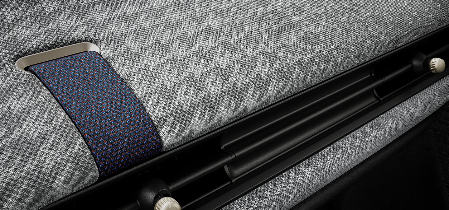 Pietuvināts skats uz instrumentu paneli ar divdimensiju adījumu MINI Cooper iekšpusē.