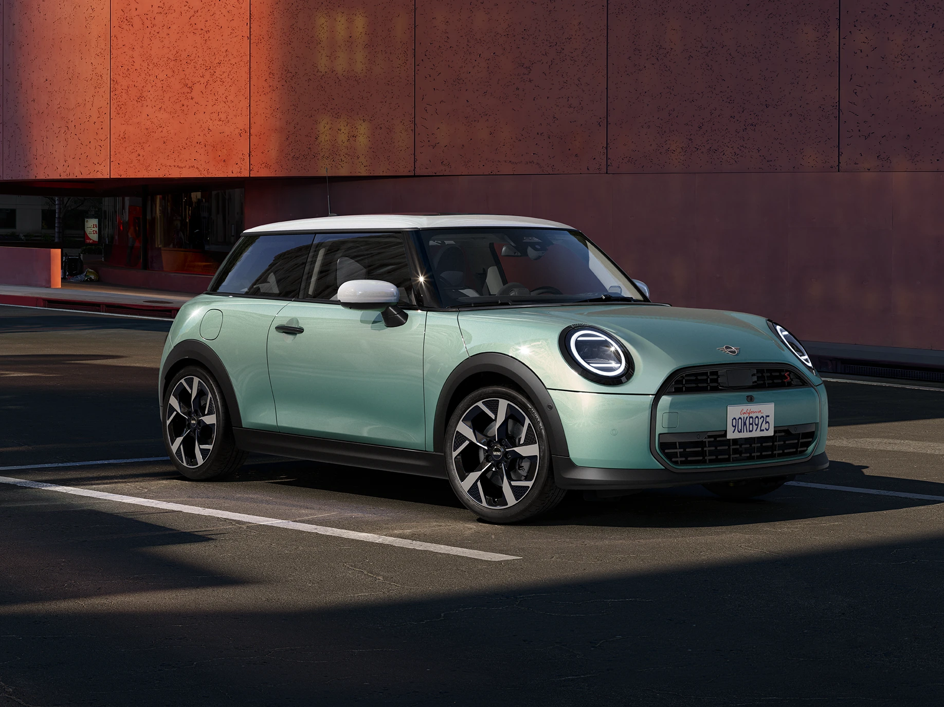 Sānskats uz MINI Cooper Ocean Wave Green krāsā ar baltu jumtu priekšēju daļu.