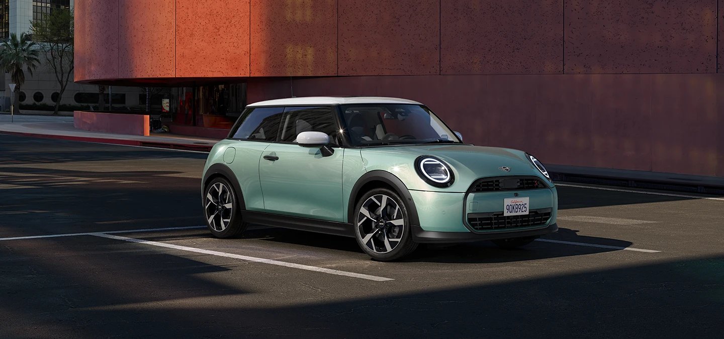 Sānskats uz MINI Cooper Ocean Wave Green krāsā ar baltu jumtu priekšēju daļu.