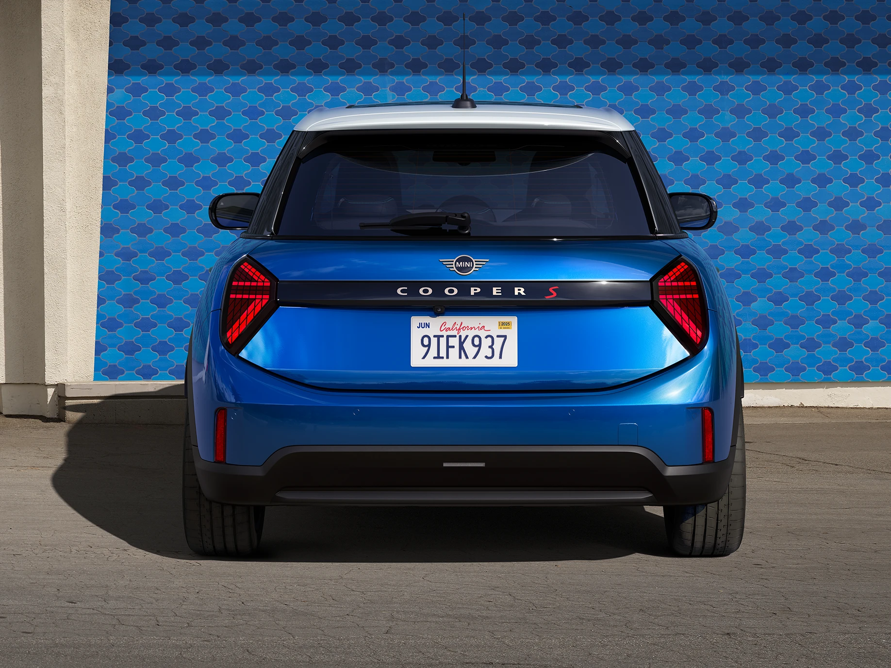 Aizmugures skats uz piecdurvju MINI Cooper Icy Sunshine Blue krāsā ar daudztoņu jumtu Blue krāsā.