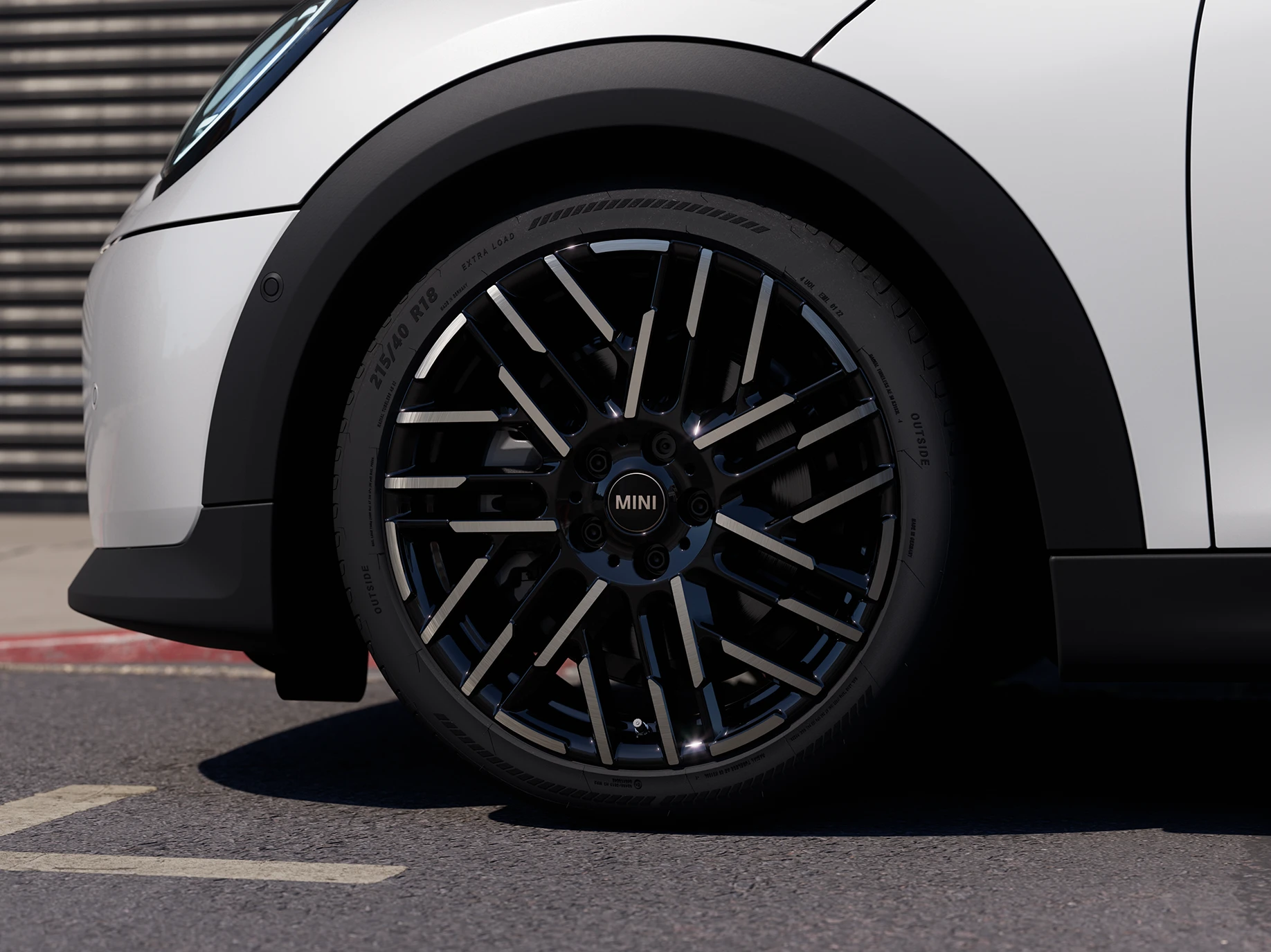 Piecdurvju MINI Cooper Nanuq White krāsā ar Night Flash Spoke divtoņu disku tuvplāns.