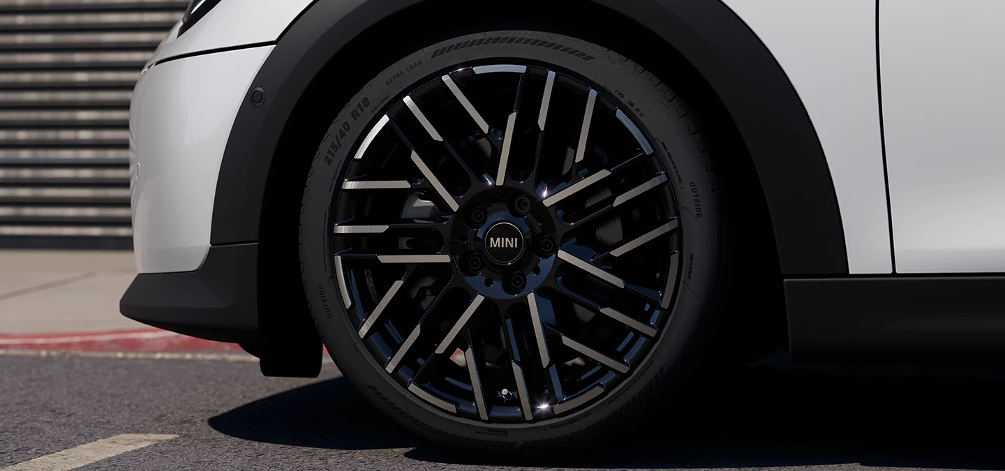 Piecdurvju MINI Cooper Nanuq White krāsā ar Night Flash Spoke divtoņu disku tuvplāns.