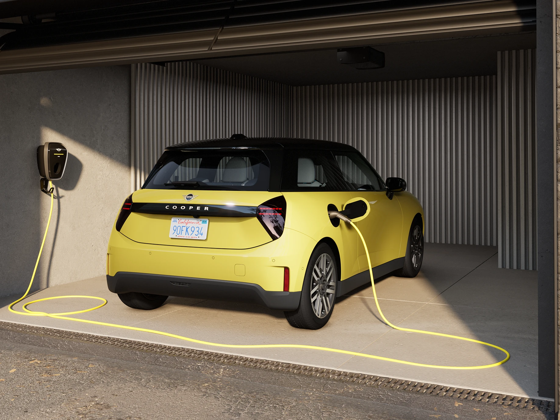 Pilnībā elektriskais MINI Cooper Sunnyside Yellow krāsā, veicot uzlādi garāžā, aizmugures skats.