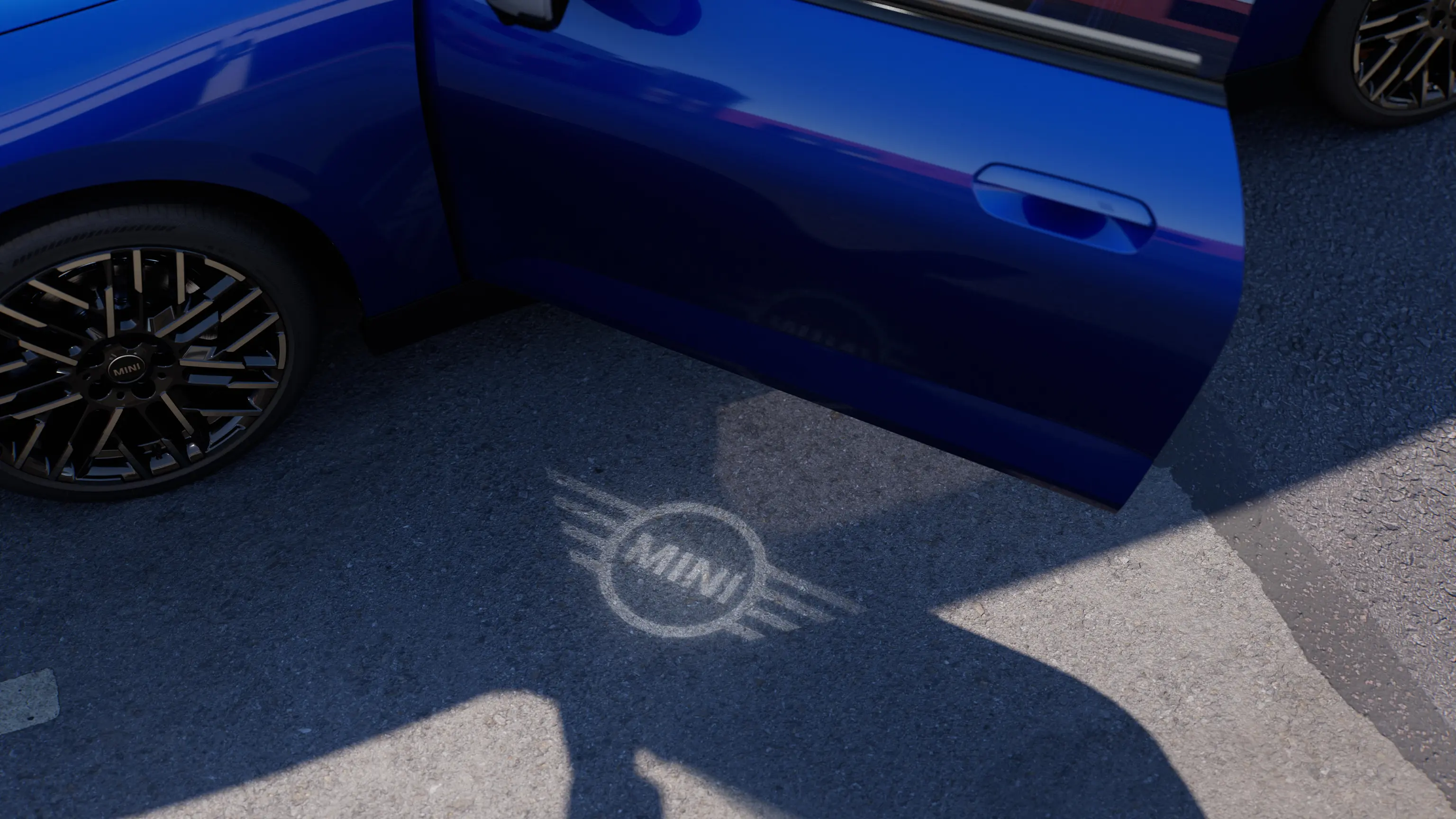 Pilnībā elektriskā MINI Cooper eksterjera skats ar atvērtām durvīm un MINI logo apsveikuma gaismu uz zemes