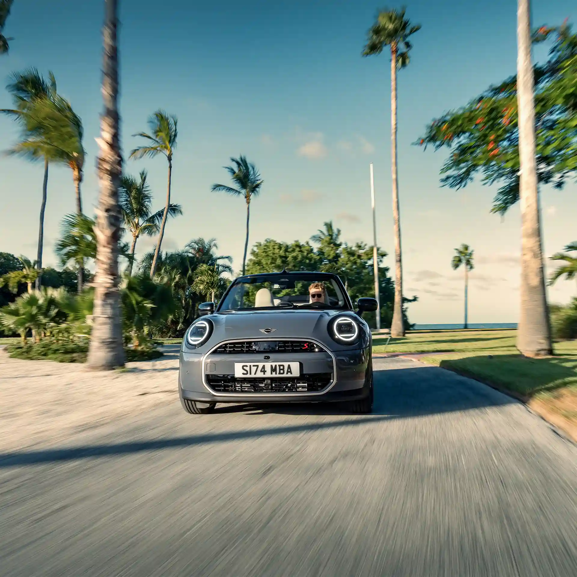 MINI Cooper Convertible priekšpuses skats Copper Grey krāsā, braucot pa ielu