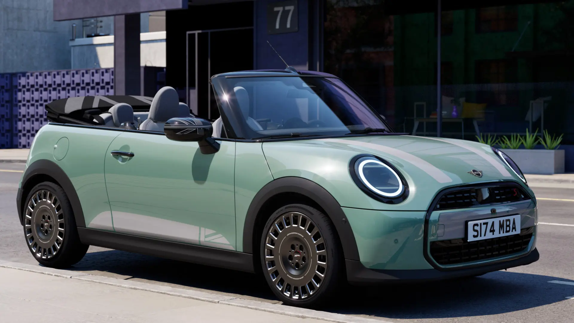 Priekšpuses sānu skats uz MINI Convertible Ocean Wave Green krāsā ar baltām MINI Heritage dzinēja pārsega uzlīmēm.