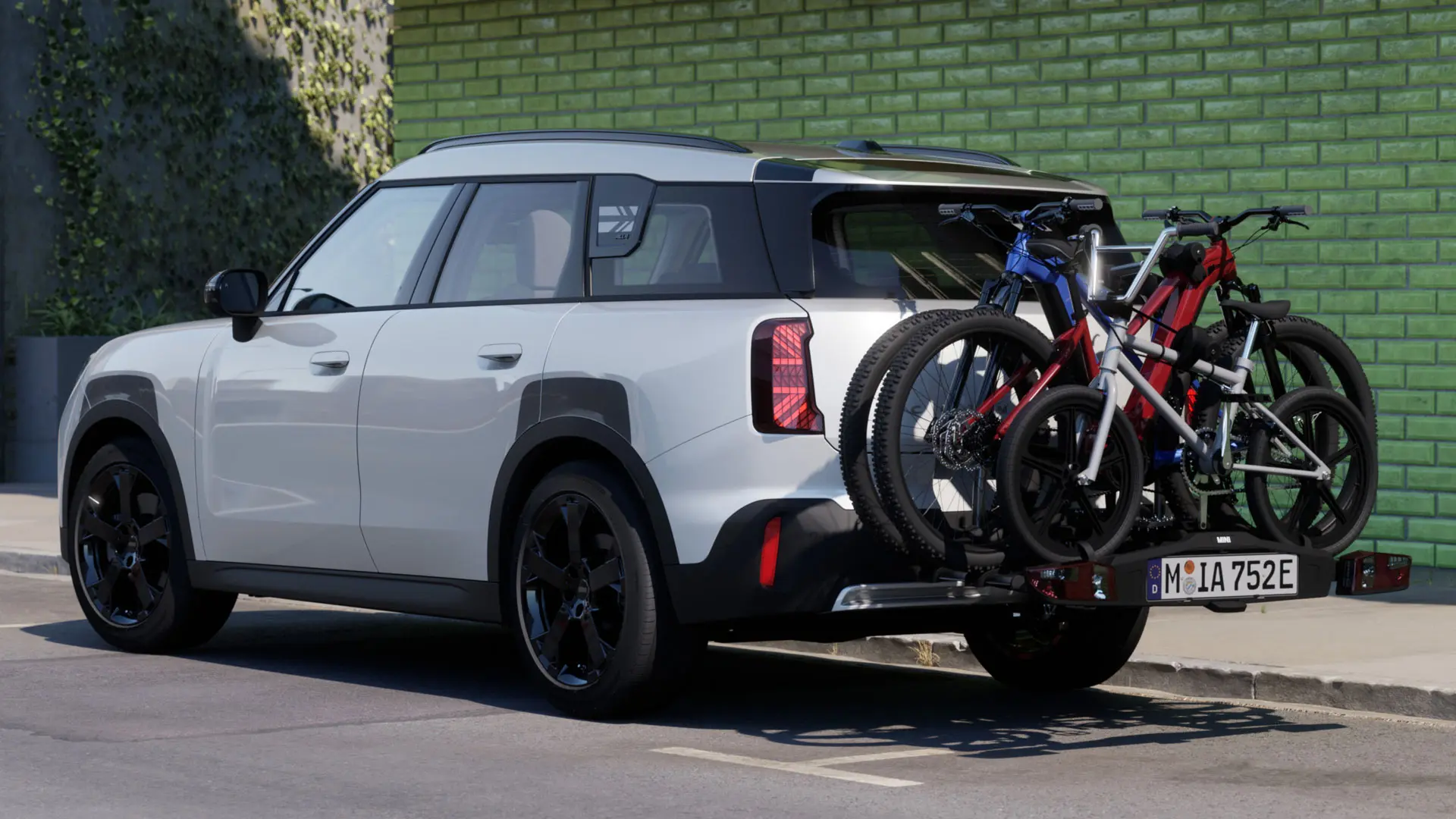 MINI Aceman Nanuq White krāsā aprīkots ar MINI aizmugurējo velosipēdu turētāju Pro 3.0, kas tur divus kalnu velosipēdus un vienu bērnu velosipēdu.