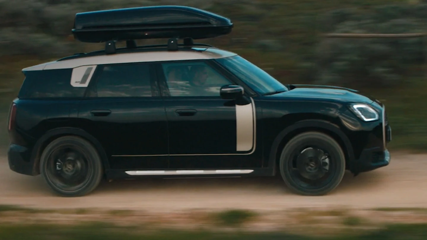 MINI Countryman metāliskā Midnight Black krāsā ar 19 collu John Cooper Works Runway Spoke diskiem Black krāsā, braucot apvidū.