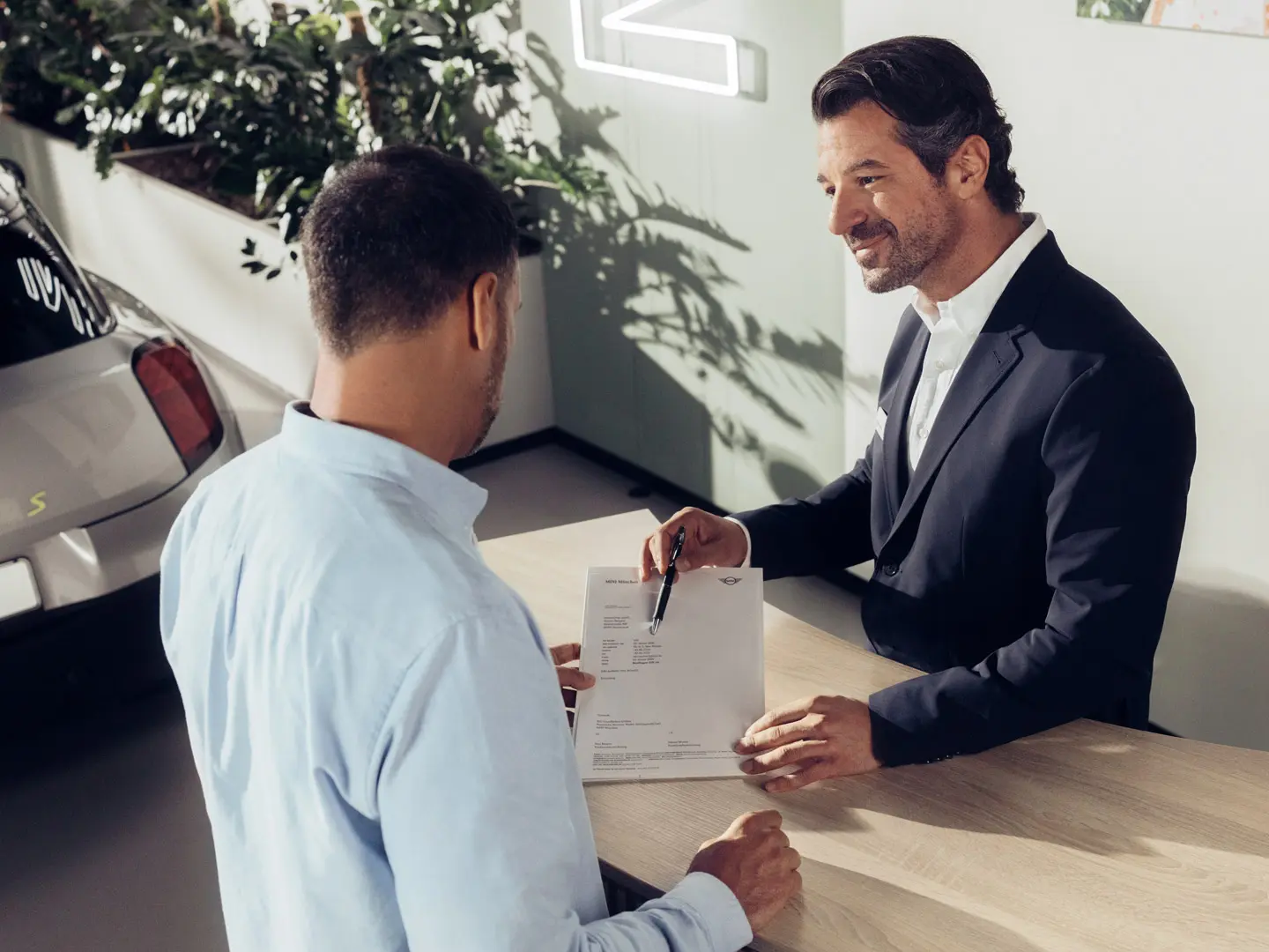 MINI partnera servisa asistents konsultē klientu par MINI riepu apdrošināšanas iespējām.