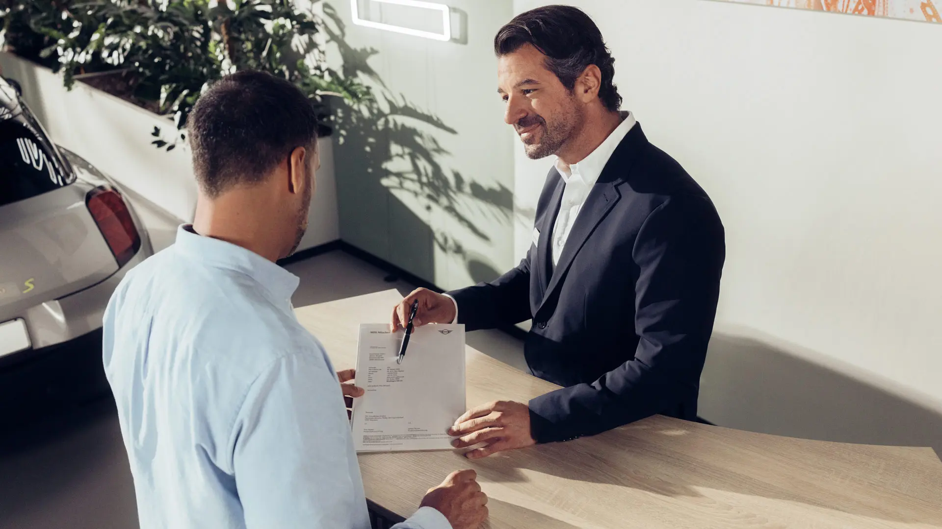 MINI partnera servisa asistents konsultē klientu par MINI riepu apdrošināšanas iespējām.