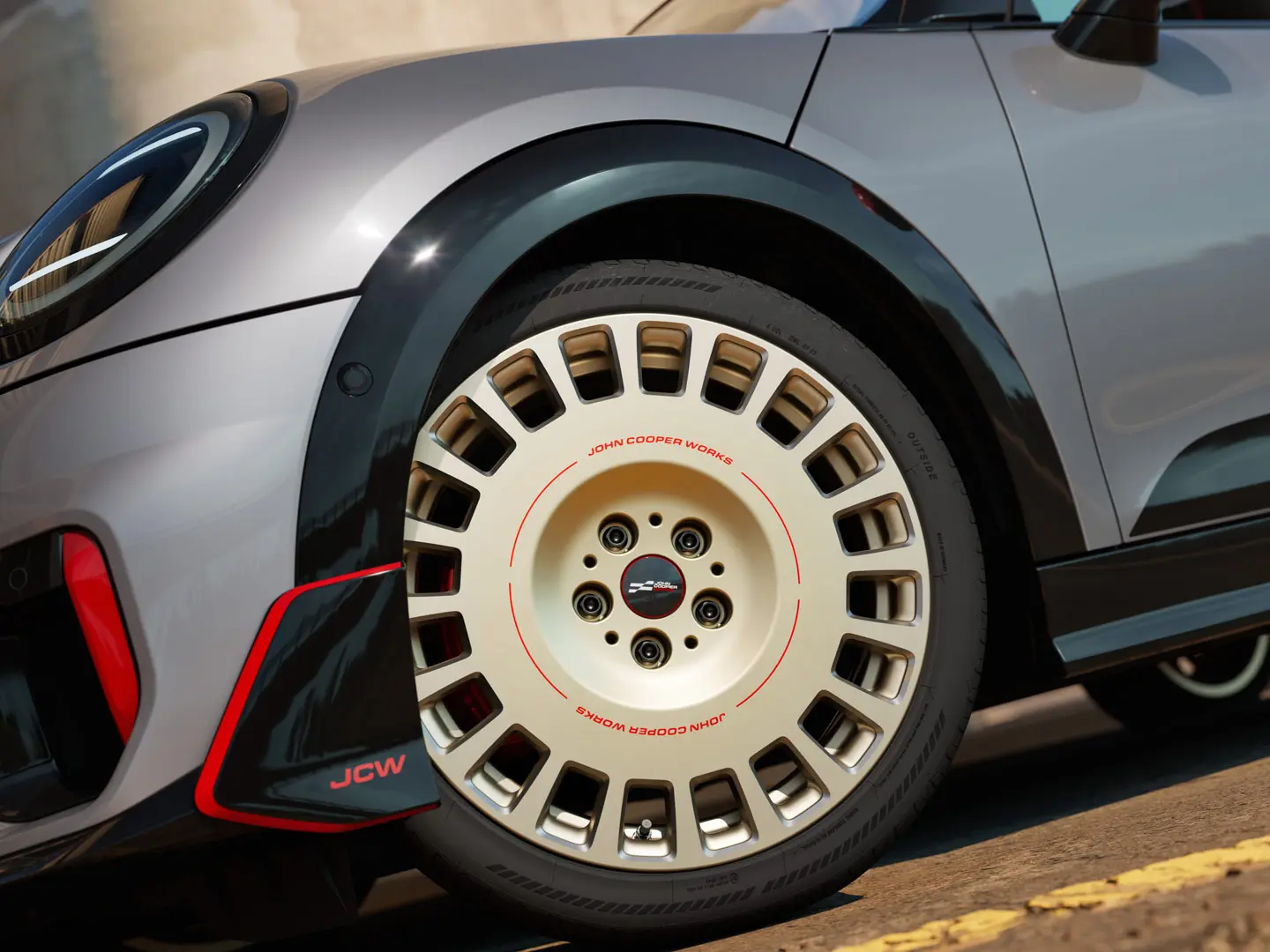 Priekšējā apakšējā spoilera un 18 collu JCW Rallye Spoke 964 diska divtoņu Vibrant Silver krāsā ar dimanta frēzējumiem detalizēts tuvplāns.