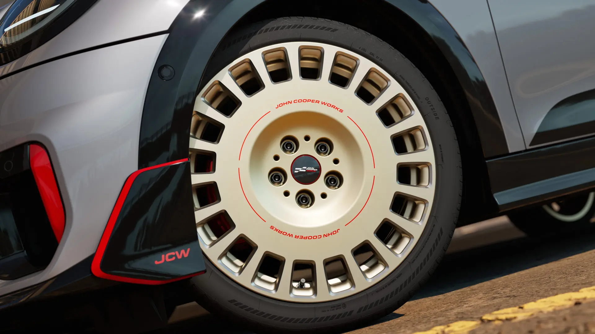 Priekšējā apakšējā spoilera un 18 collu JCW Rallye Spoke 964 diska divtoņu Vibrant Silver krāsā ar dimanta frēzējumiem detalizēts tuvplāns.