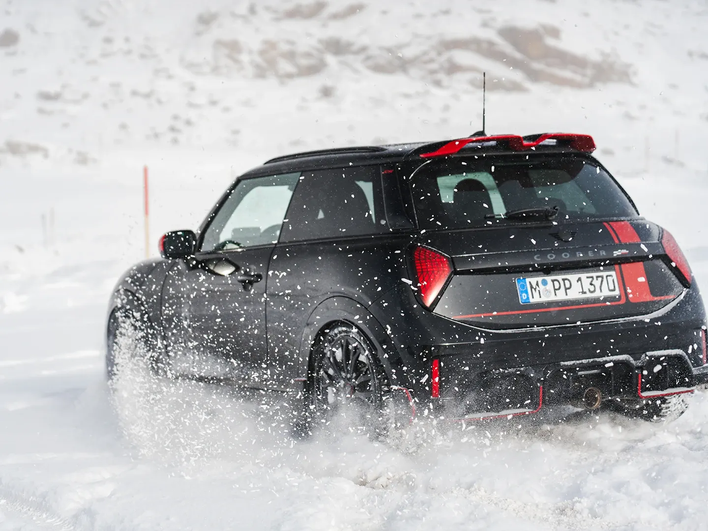 MINI Cooper JCW aizmugures skats, braucot pa sniegu.