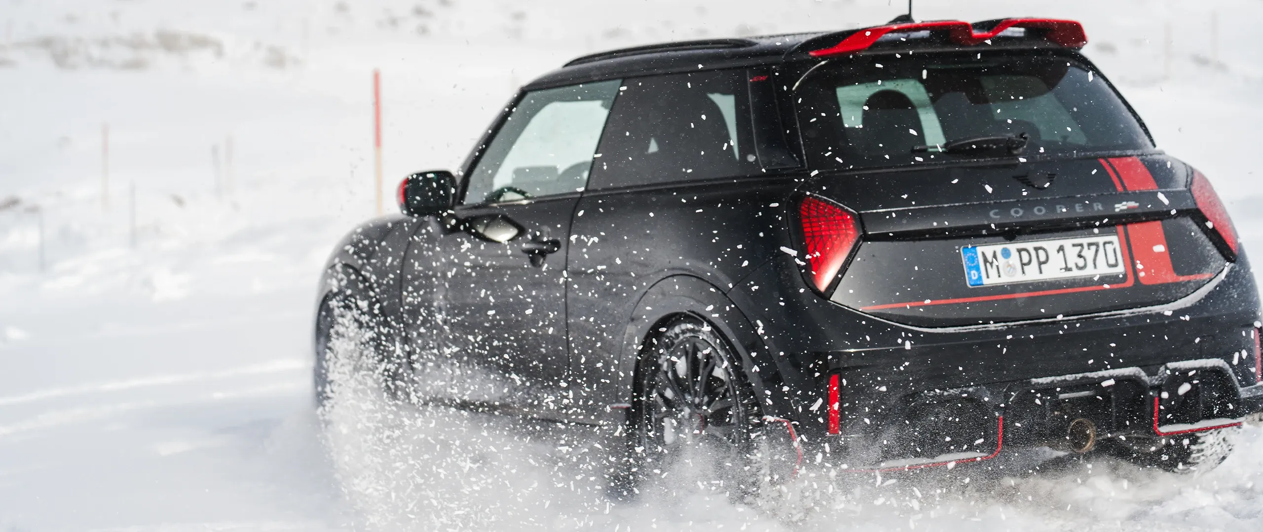 MINI Cooper JCW aizmugures skats, braucot pa sniegu.