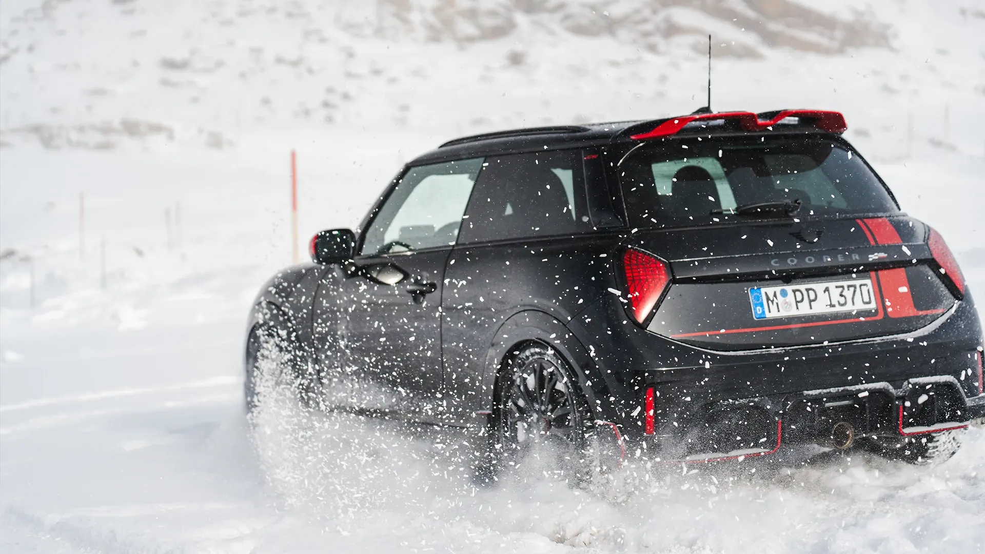 MINI Cooper JCW aizmugures skats, braucot pa sniegu.