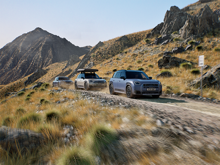 Attēls, kurā redzami vairāki MINI Countryman Untamed Edition modeļi, kas brauc pa kalniem bezceļu apstākļos.
