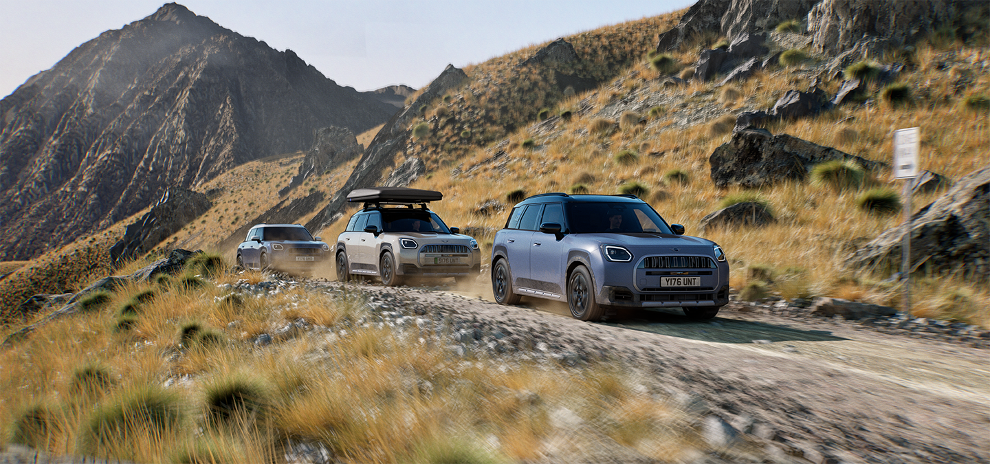 Attēls, kurā redzami vairāki MINI Countryman Untamed Edition modeļi, kas brauc pa kalniem bezceļu apstākļos.