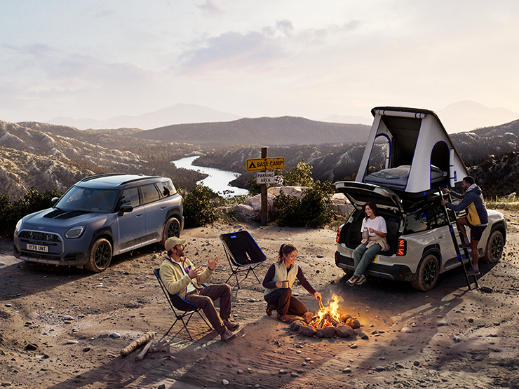 Attēls, kurā saulrieta laikā redzami divi kalnā uzbraukuši MINI Countryman Untamed Edition automobiļi.